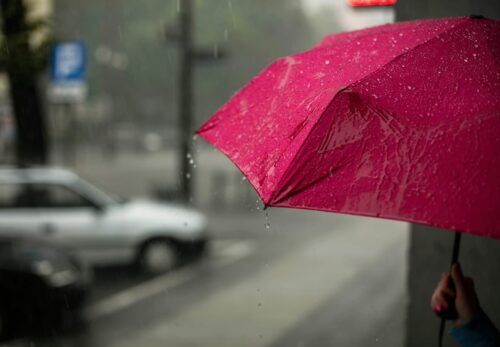Un parapluie rouge sous la pluie représentant une travailleuse du sexe