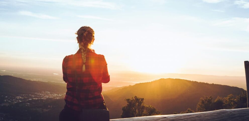 Une femme se repose en regardant un coucher de soleil.