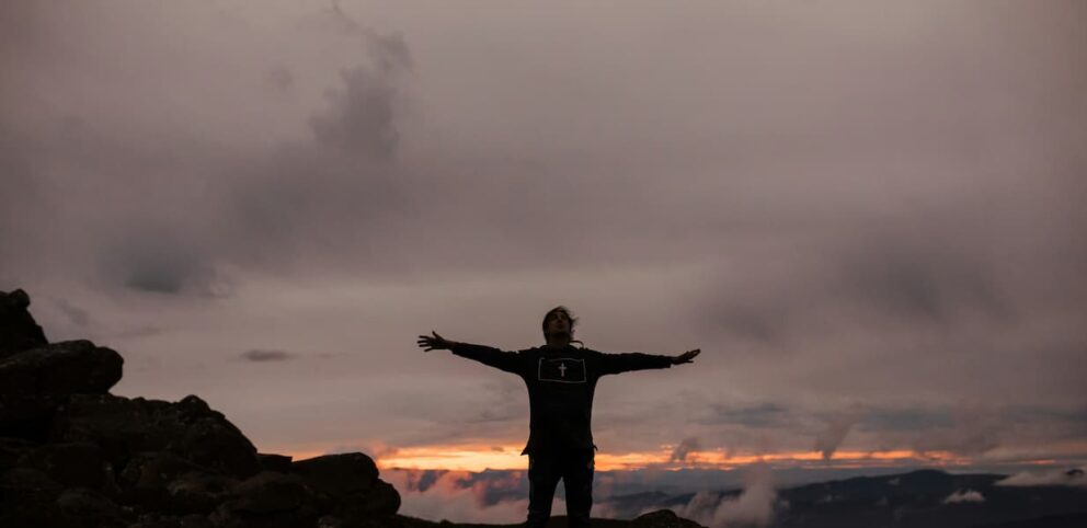 Un homme sur une montagne célébrant sa spiritualité.