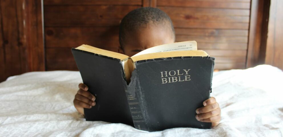 Un enfant, à qui on a transmis la foi, lit la bible.