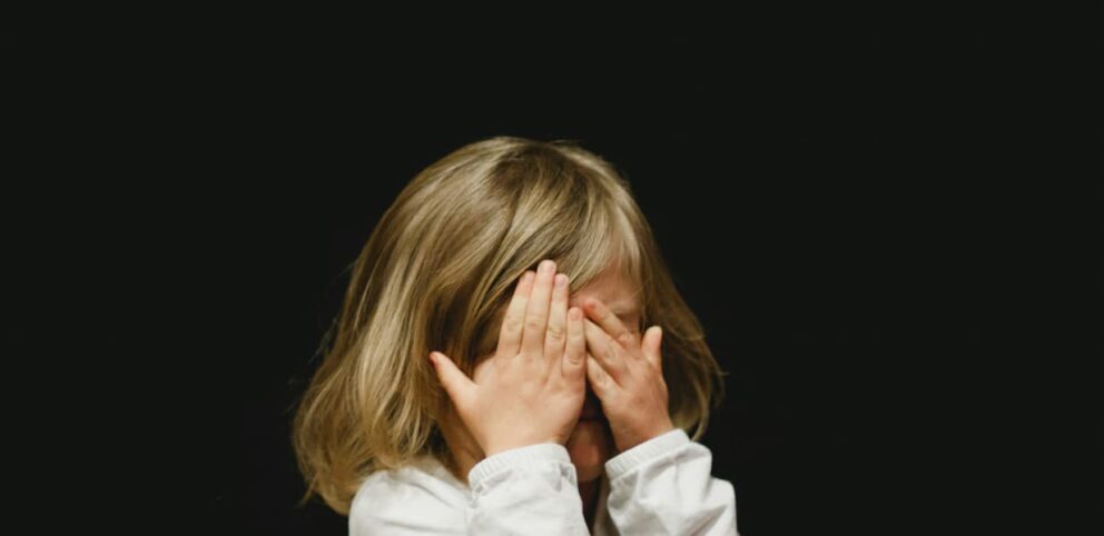 Une fillette se cache les yeux pour ne pas voir les effets de la réputation.