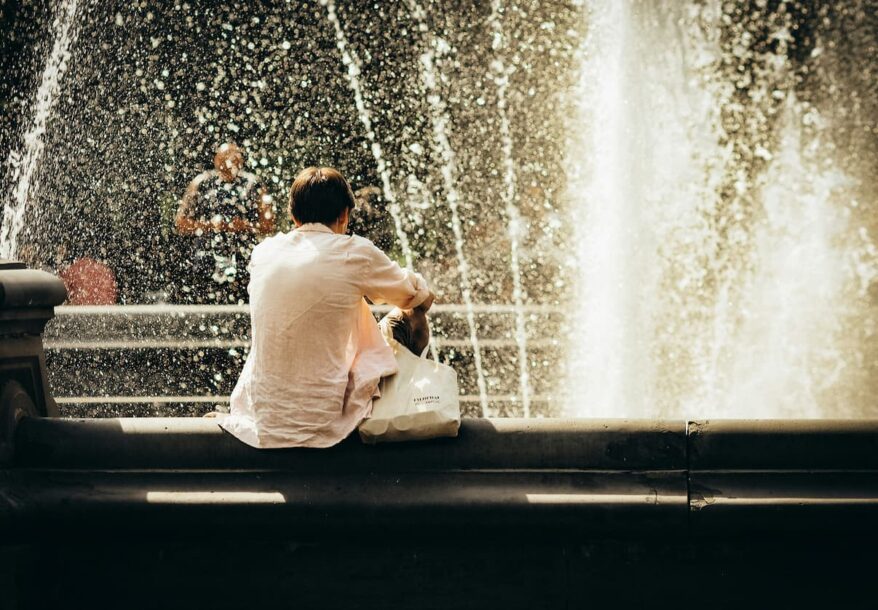 Un homme devant une fontaine d'eau profitant des joie de l'été.