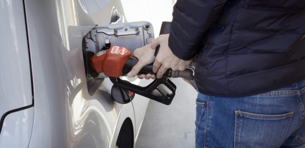 Une personne qui fait le plein d'essence représentant notre dépendance au pétrole.