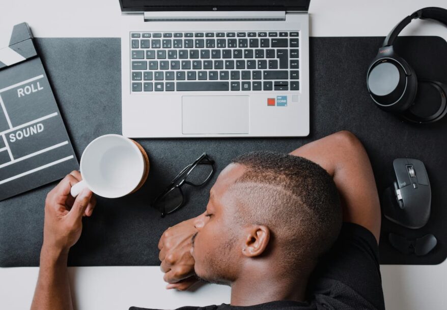 Un homme en état de procrastination, couché sur son pupitre.